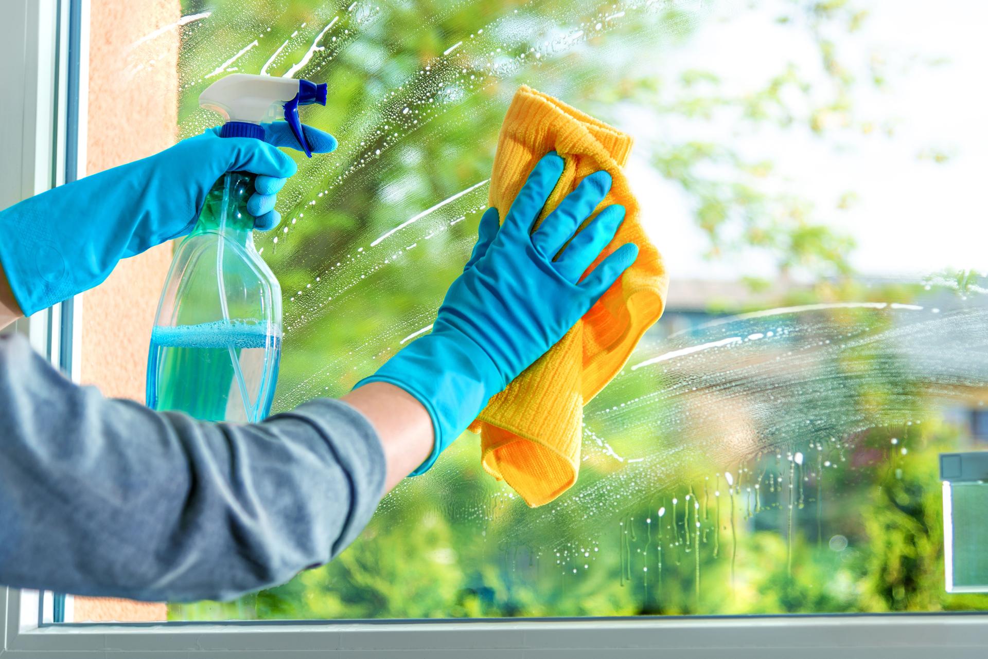 Maid Cleaning window pane with detergent and microfiber 