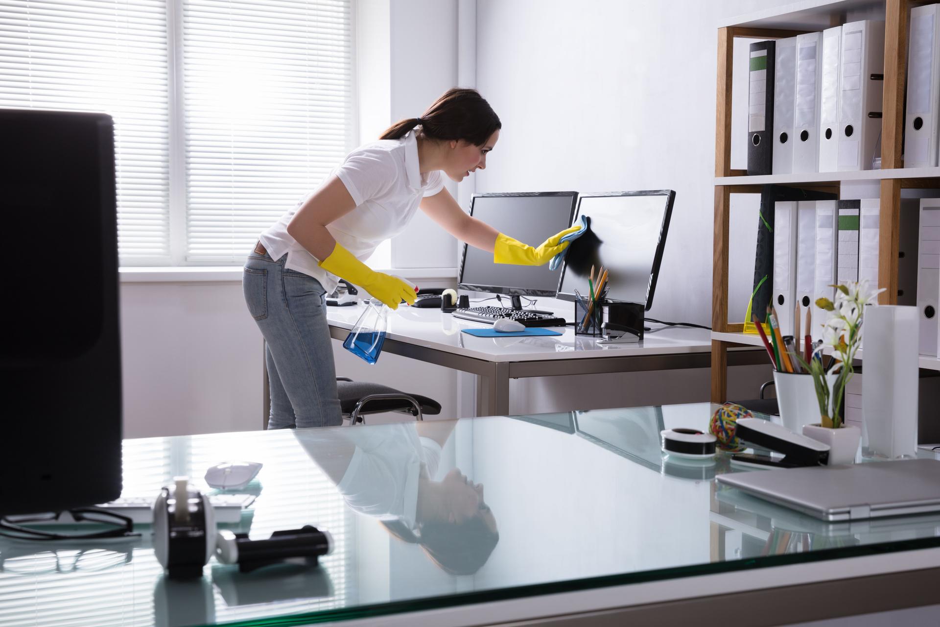 Woman Cleaning Computer and desktop In Office 